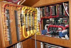 the inside of a wooden cabinet with many wires and other electrical equipment in it's compartments