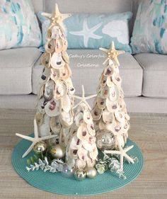 three christmas trees made out of seashells on a table