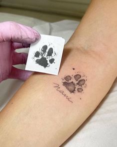 a person with a tattoo on their arm and paw prints on the wrist, next to a small piece of paper that says i love you