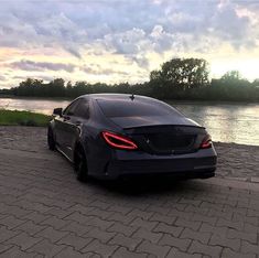 a black car parked on the side of a road next to a body of water