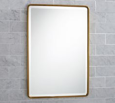 a bathroom mirror mounted to the side of a wall next to a tiled counter top