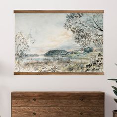 a painting hanging on the wall above a dresser in a room with white walls and wooden furniture