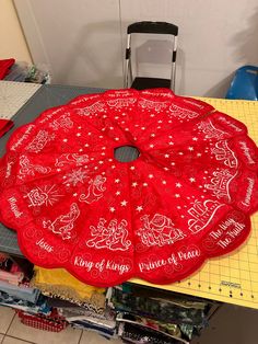 a large red christmas tree skirt sitting on top of a table next to a chair