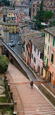 a man walking up some steps in the middle of a city with buildings on both sides