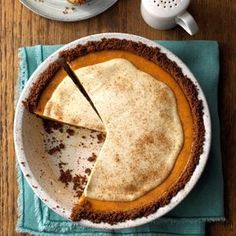 a pie sitting on top of a wooden table next to a cup and saucer