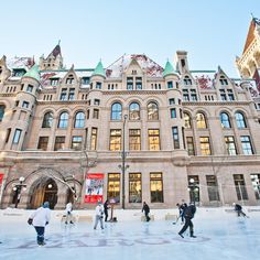 people skating on an ice rink in front of a large stone building with many windows