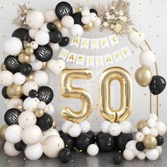 the 50th birthday balloon arch is decorated with black, white and gold balloons that spell 50