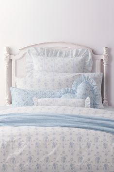 a bed with blue and white comforters on top of it next to a night stand