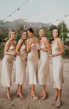 the bride and her bridesmaids are posing for pictures in front of string lights