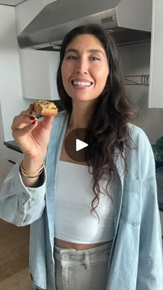 a woman holding a doughnut in her right hand and looking up at the camera