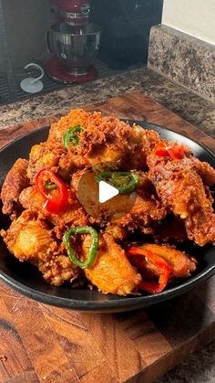 a black plate filled with fried food on top of a wooden table next to a blender