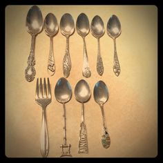 an assortment of spoons and forks are arranged in a row on a beige background