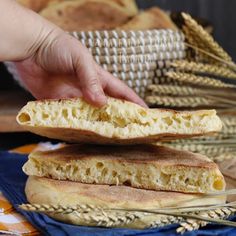 a person reaching for some bread on top of a blue cloth with wheat stalks in the background