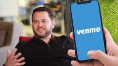 a man sitting in a chair holding up a cell phone with the word venno on it