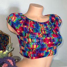 a mannequin wearing a multicolored knitted top next to a mirror