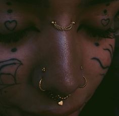 a close up of a person with tattoos on their face, nose and nose piercings