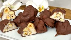 there are many pieces of chocolate with nuts in it on the plate next to flowers