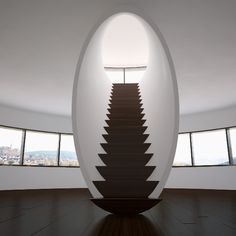 a staircase in the middle of a room with large windows