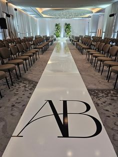 a long white aisle with chairs lined up on each side and the word ab written in black