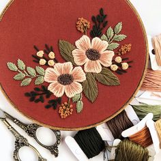 embroidery kit with flowers and scissors on the table next to thread, spools and needles