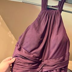 a woman is holding up a purple dress