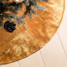 a gold christmas tree skirt with ornaments on it