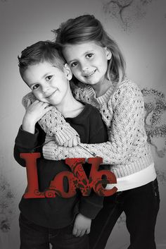 two children hugging each other with the word love written in red and black on it