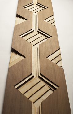 an intricate wooden design on the wall in a room with white walls and flooring