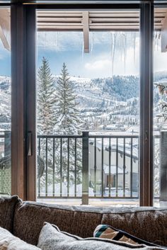 a living room filled with furniture next to a window covered in snow and icicles