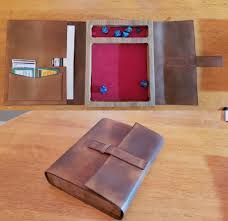 an open brown leather book sitting on top of a wooden table next to a wallet