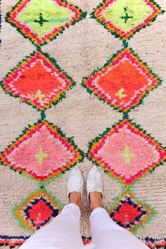 a person standing in front of a colorful rug on the floor with their feet up