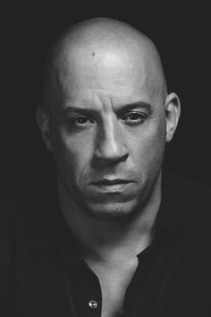 black and white photograph of a bald man looking at the camera with an intense look on his face