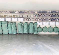 several bags are lined up against the wall in a storage area with bins and shelves