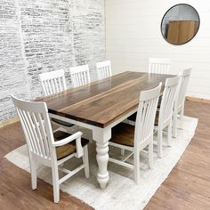 a dining room table with white chairs and a brown wooden centerpiece on top of a rug