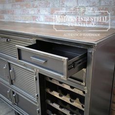 an industrial style cabinet with drawers and wine racks in the bottom drawer, on display against a brick wall