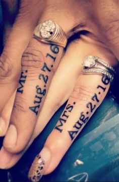 two people holding hands with tattoos on their fingers and the other hand has writing on it