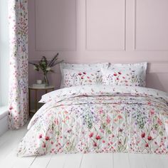 a bedroom with pink walls and floral bedding