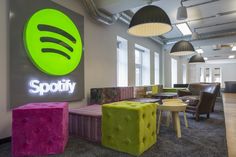 brightly colored stools in front of the spotify logo at an office building lobby