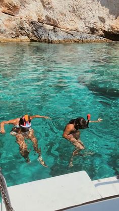 two people are swimming in the clear blue water