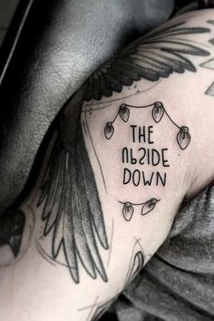 a man with a tattoo on his arm that reads the upside down and an angel wing