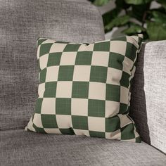 a green and white checkered pillow on a gray couch