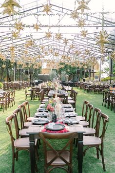 a long table set up with plates and place settings for an outdoor wedding reception in a tented area