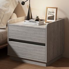 a nightstand with two books on it next to a bed