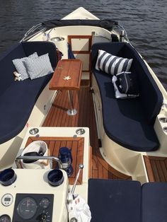 the inside of a boat with blue cushions and pillows on it's back end