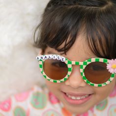 **SHIPS IN 1-2 BUSINESS DAYS** Listing is for one pair of sunglasses with personalization, and flower charm. Made to order.  Total width of flower shape on sunglasses is 5.11 inches. Frame width and height are 5.31 inches.  Toddler/ Kids sunglasses. Suitable for ages 3-8 Light to wear. Made of AC and PC material. UV 400 If you want a different color flower added, message me :) Retro Sunglasses With Tinted Lenses For Gift, Retro Sunglasses With Tinted Lenses As Gift, Retro Sunglasses With Tinted Lenses As A Gift, Custom Name Fun Sunglasses For Summer, Playful Party Sunglasses Personalized, Playful Personalized Sunglasses For Party, Personalized Playful Sunglasses For Party, Playful Personalized Sunglasses For Parties, Playful Polarized Sunglasses For Birthday