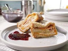 two pastries on a plate with jam and spoons in the background, ready to be eaten