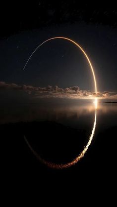 a rocket is flying through the night sky with its tail extended and it's reflection in the water