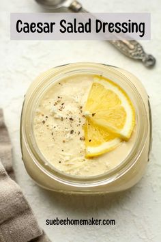 a close up of a bowl of food with a lemon slice on top and the words caesar salad dressing above it