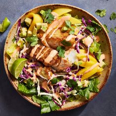 a bowl filled with meat and vegetables on top of a blue tablecloth next to limes