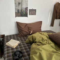 an unmade bed in a small room with pictures on the wall above it and a pair of headphones